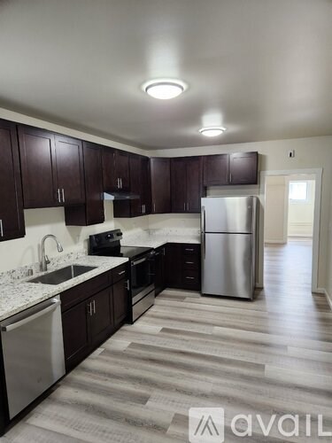 A kitchen with dark wood cabinets and a stainless steel refrigerator.