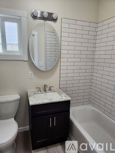 A bathroom with a white toilet, a sink with a marble top, and a bathtub.