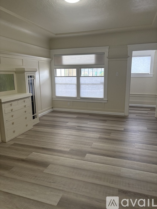 A room with wooden flooring and a window overlooking a street.