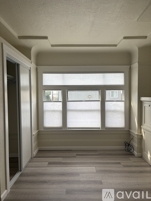 A room with a large window and a bicycle in the corner.