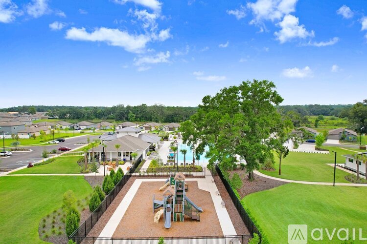 A park with a playground and a fence in the foreground.