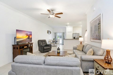 A living room with a grey sofa, a wooden table, a television, and a painting on the wall.