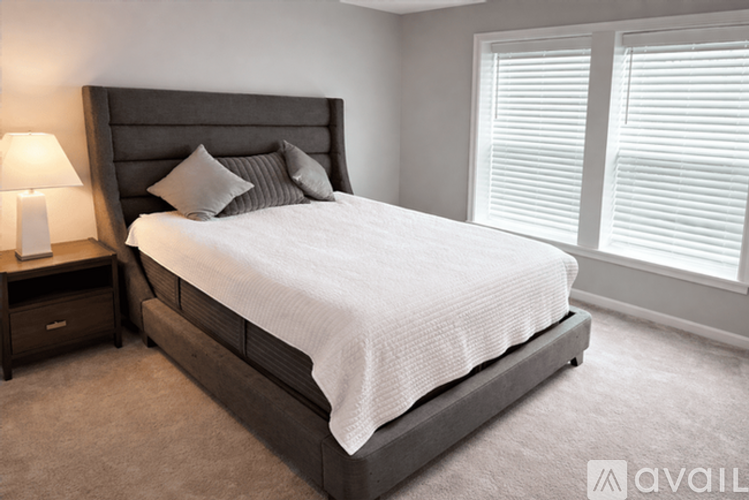 A bedroom with a large bed and a nightstand with a lamp.