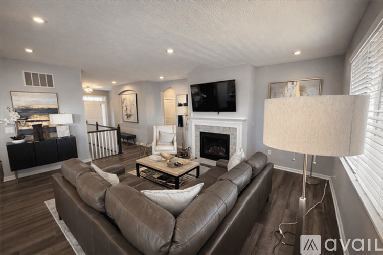 A living room with a brown leather couch and a fireplace.