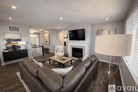 A living room with a brown leather couch and a fireplace.