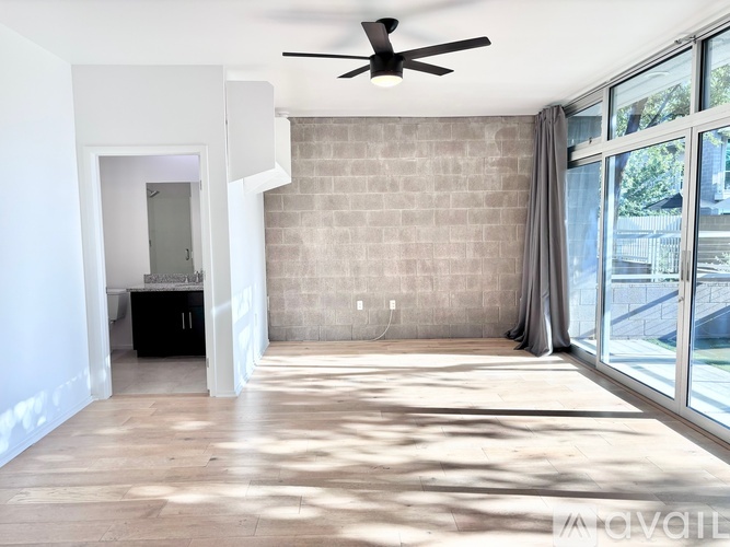 A spacious room with a ceiling fan and a large window.