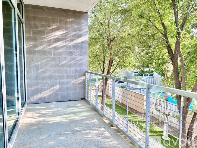 A balcony with a metal railing and a view of a pool and trees.