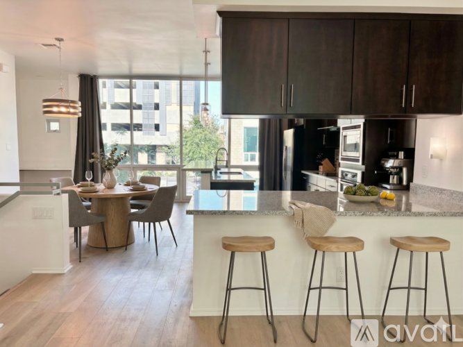 A modern kitchen with dark wood cabinets and a large island with three stools.