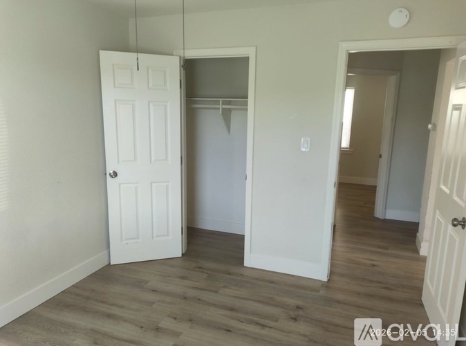 A room with a white door and a wooden floor.