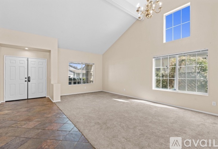 A spacious room with a chandelier, two doors, and a large window with a view of the outdoors.