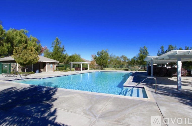 A large outdoor swimming pool surrounded by trees and a covered area.