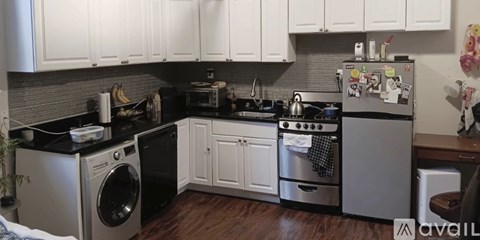 A kitchen with white cabinets and a black countertop.