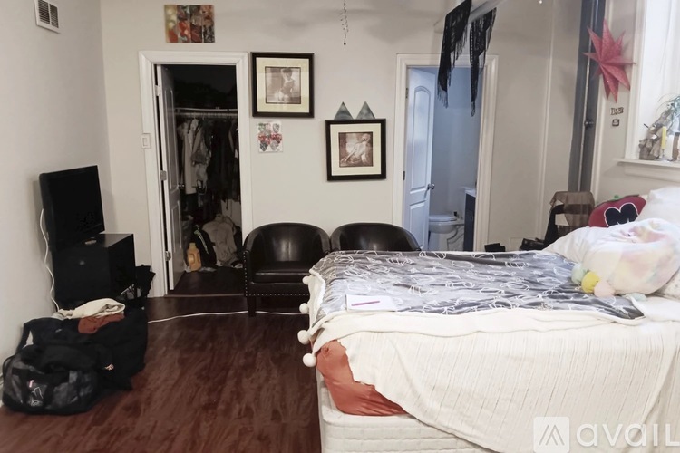 A bedroom with a bed, chair, and a television.