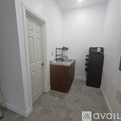 A small room with a door, a cabinet, and a fridge.