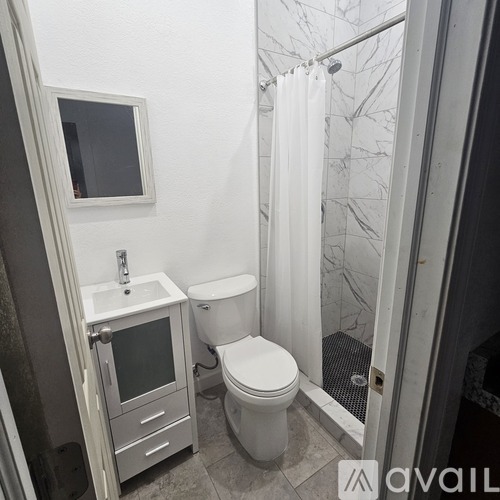 A bathroom with a toilet, sink, and shower.