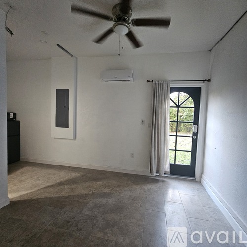 A room with a ceiling fan, a window with curtains, and a door leading outside.