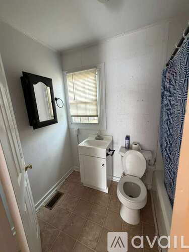 A bathroom with a toilet, sink, and mirror.