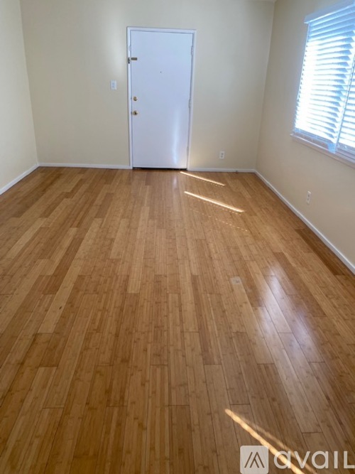 A room with a white door and wooden flooring.