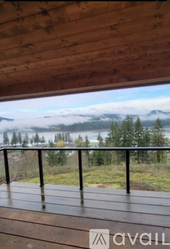 A wooden deck overlooks a lake with mountains in the distance.