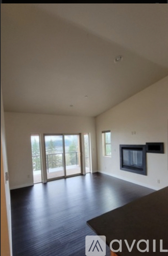 A spacious living room with a television and sliding glass doors.