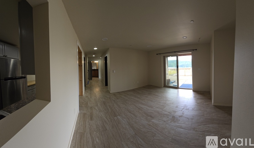 A spacious room with a long hallway leading to a sliding glass door.