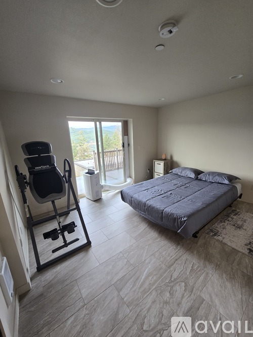 A bedroom with a bed, chair, and a window overlooking a balcony.