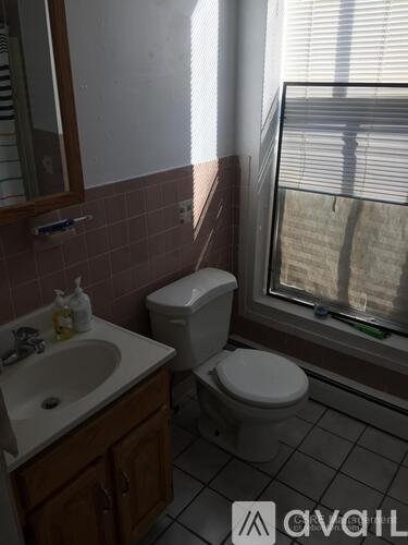 A bathroom with a toilet, sink, and window.