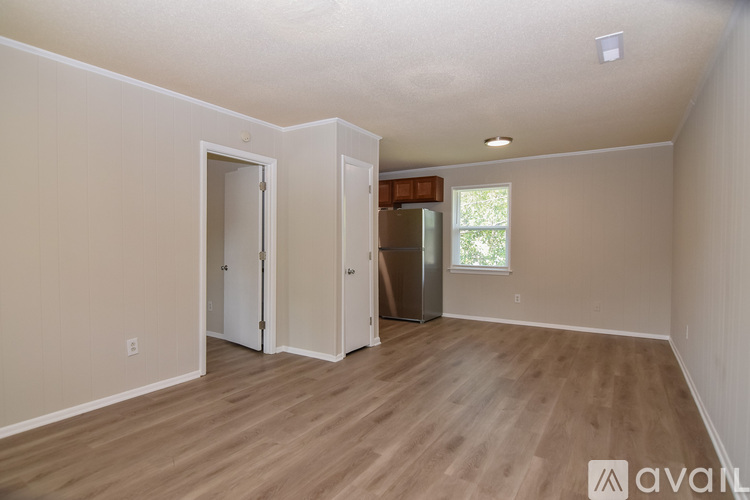 A room with wooden flooring and a window with a view of trees.