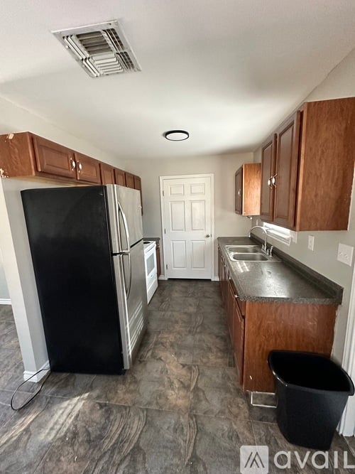 A kitchen with a black fridge and brown cabinets.