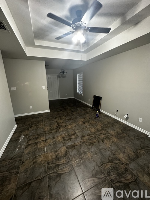 A room with a ceiling fan and tile flooring.