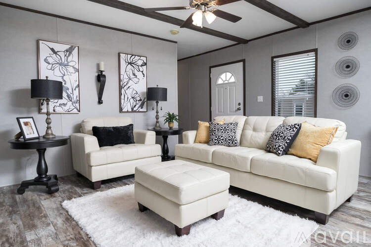 A living room with a white couch, a black table, and a white rug.