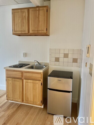 A kitchen with wooden cabinets and a black dishwasher.