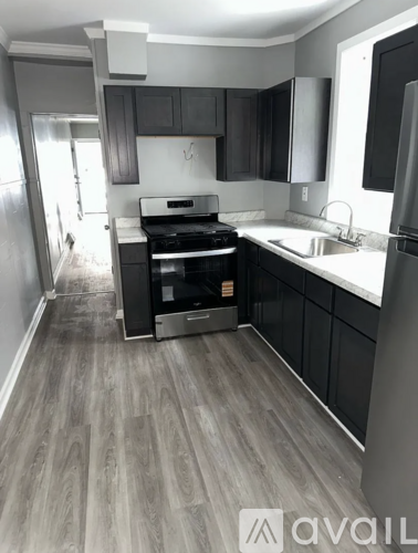 A kitchen with a stove, sink, and refrigerator.