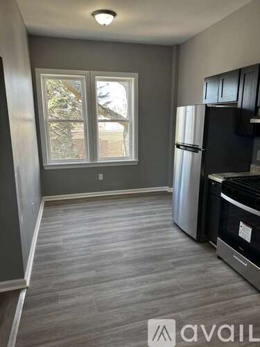 A kitchen with a black fridge and a window with a view of a tree.
