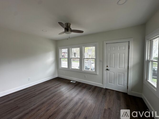 A room with a ceiling fan and wooden flooring.