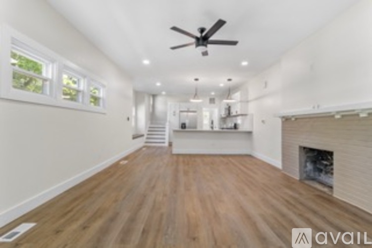 A spacious room with wooden flooring and a ceiling fan.