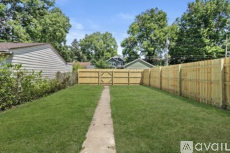 A wooden fence runs along a grassy area in front of a house.