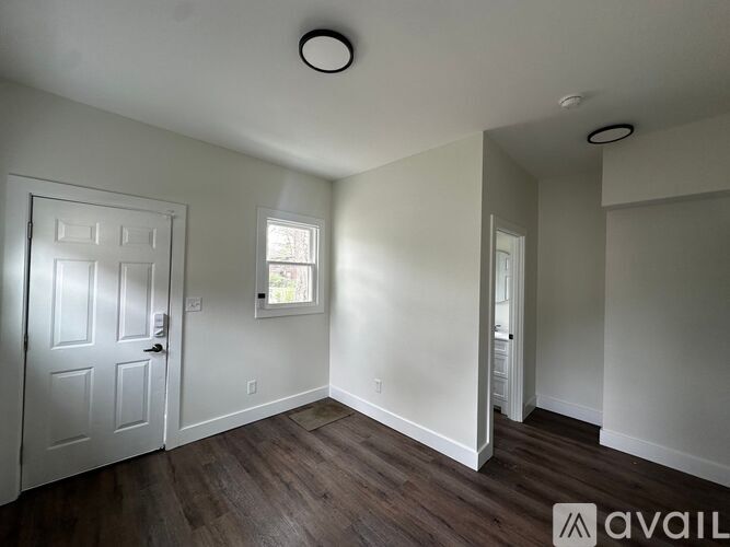 A room with a door, a window, and a wooden floor.