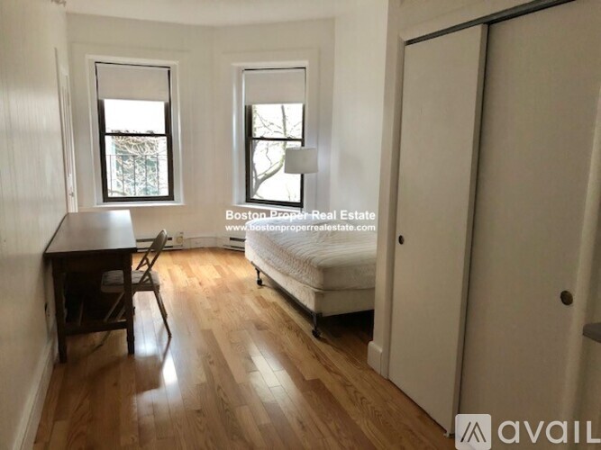 A room with wooden floors, a desk, a chair, and a bed.