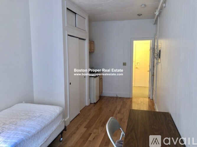 A bedroom with a bed, chair, and wooden floor.