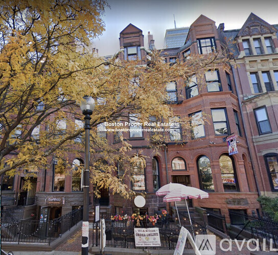 A large, historic-looking building with a sign that reads "Boston Proper Real Estate" in front of it.