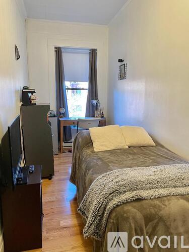 A bedroom with a bed, a television, and a window.