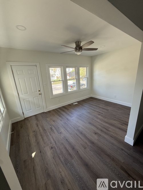 A room with a ceiling fan and wooden flooring.