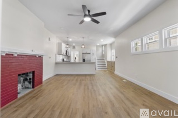A spacious room with wooden floors and a ceiling fan.