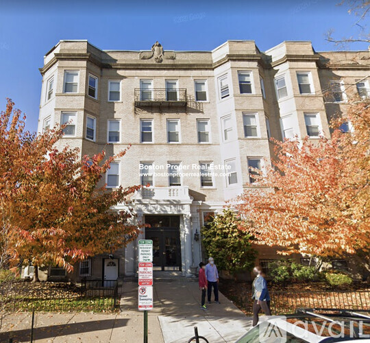 A large white building with a balcony on the second floor is labeled Boston Proper Real Estate.