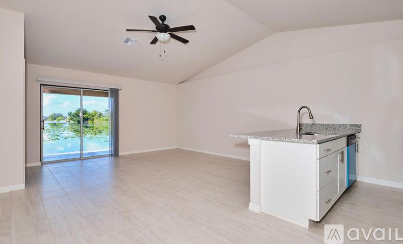 A spacious room with a ceiling fan and a kitchenette with a sink.