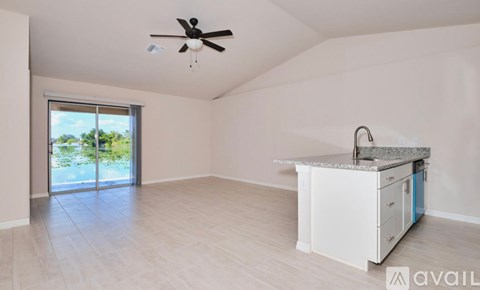 A spacious room with a ceiling fan and a kitchenette with a sink.