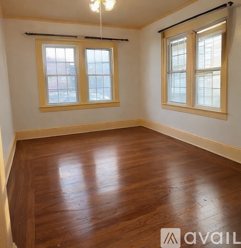 A room with wooden floors and two windows.