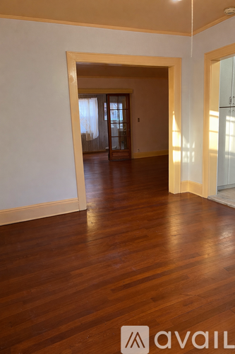 A room with wooden floors and a doorway leading to another room.