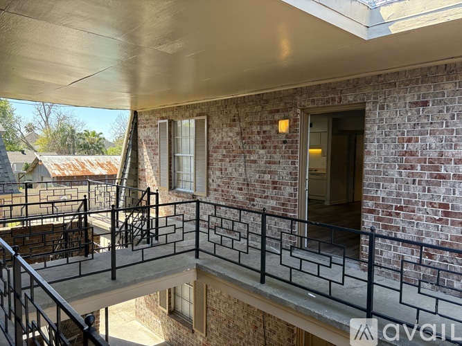 A balcony with a metal railing and a brick wall.